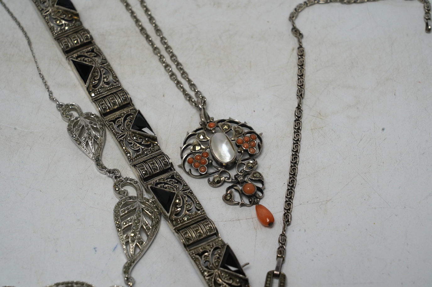 An early to mid 20th century white metal, mother of pearl and coral bead set drop pendant necklace, overall 60cm, together with two white metal and marcasite set necklaces, one stamped 925 and a German 935 marcasite and